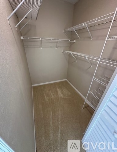 Empty walk-in closet with white shelving.