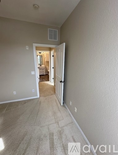 A hallway with a carpeted floor and white walls leading to a doorway.