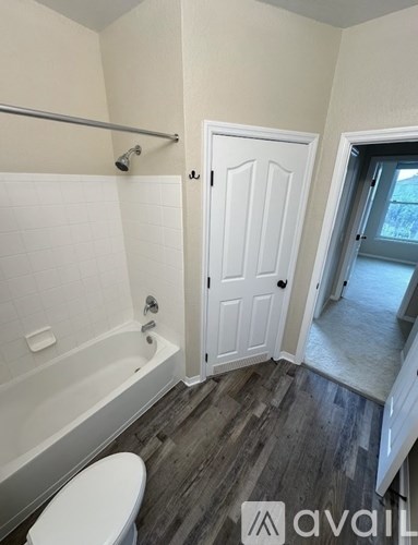 A bathroom with a white toilet, a white bathtub, and a white door.