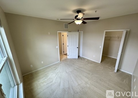A room with a ceiling fan and a door in the middle.