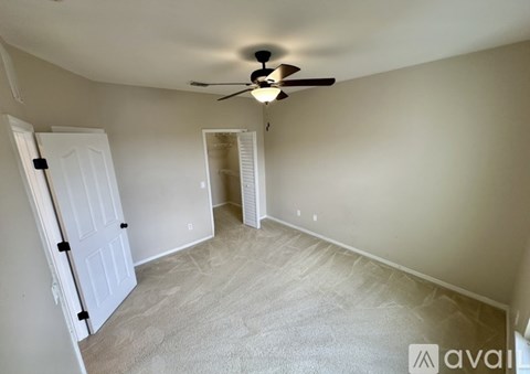 A room with a ceiling fan and carpeted floor.