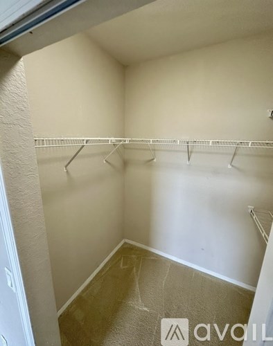 A small, empty room with a carpeted floor and a row of hangers on a rack.