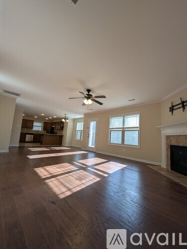 A spacious living room with a fireplace and a fan on the ceiling.