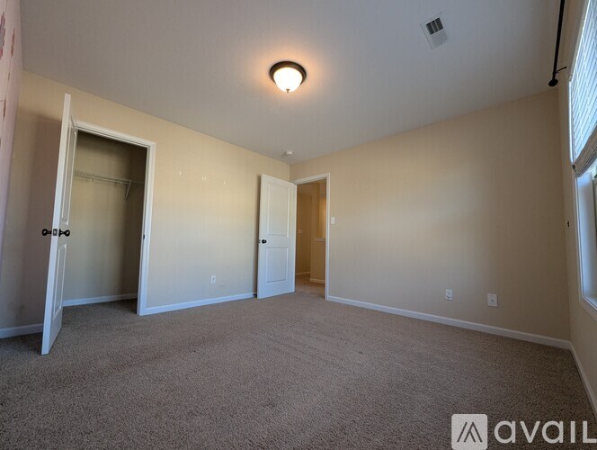 A spacious room with carpeted floor and two doors.