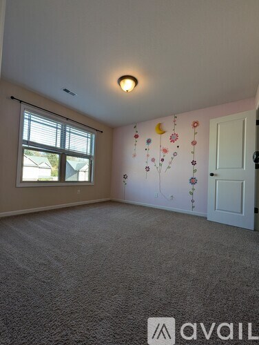 A room with a carpeted floor and a wall with floral wallpaper.