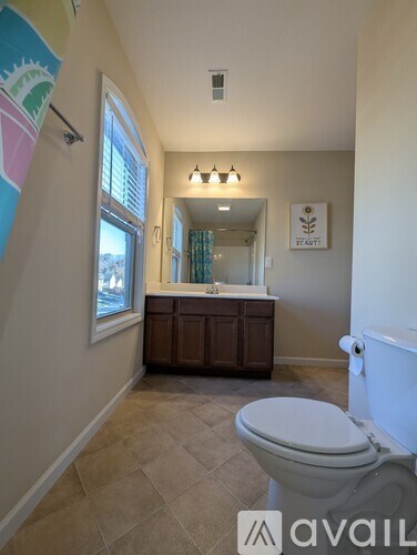 A bathroom with a toilet, sink and a mirror.