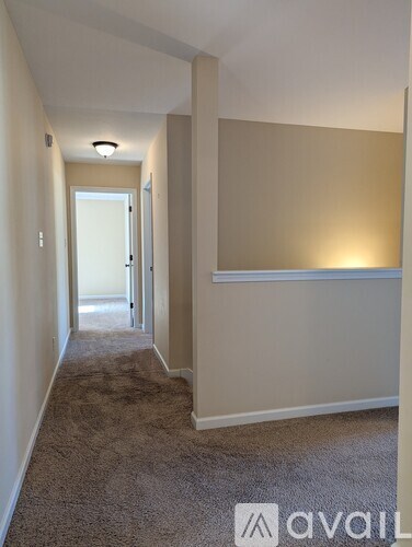 A hallway with a carpeted floor and white walls.