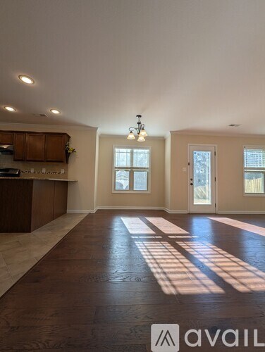 A large, empty room with wooden floors and a chandelier.