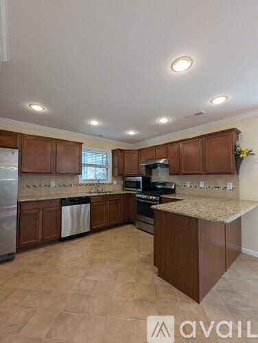 A kitchen with brown cabinets and a marble countertop.