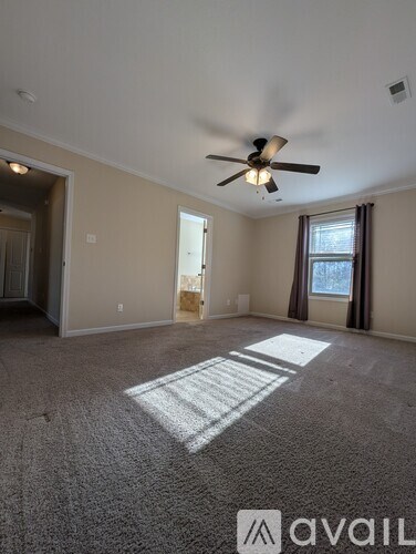 A room with a ceiling fan and a window with sunlight coming through.