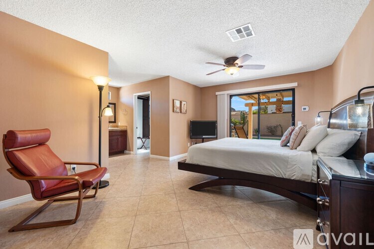 A bedroom with a bed, chair, and a ceiling fan.
