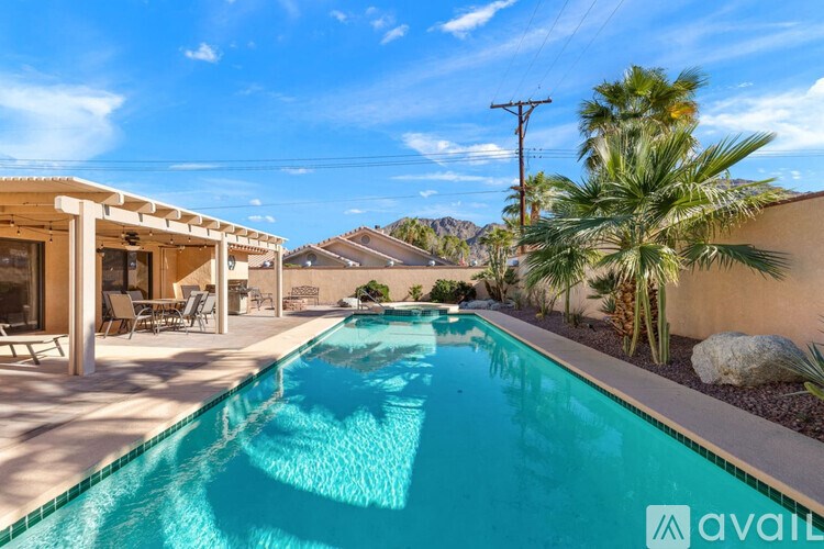 A pool in a backyard with a house and palm tree in the background.