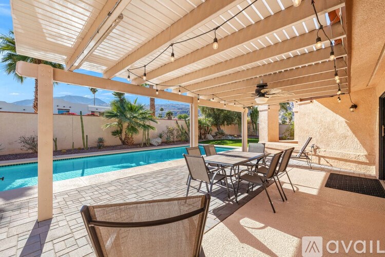 A patio with a table and chairs overlooking a pool.