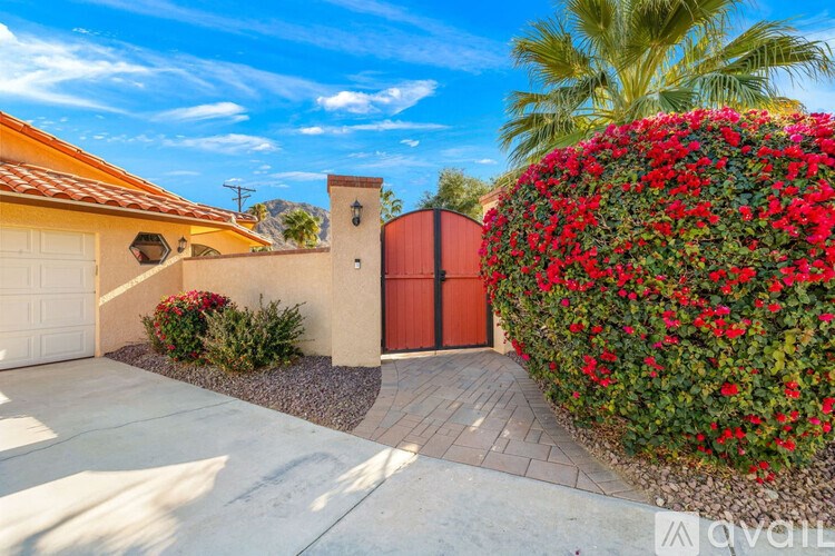 A house with a red door and a red wall covered in flowers.