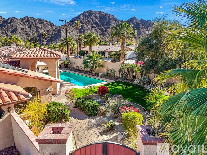 A house with a pool surrounded by greenery and mountains in the background.