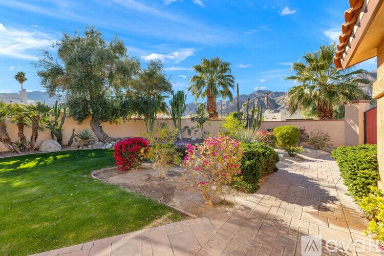 A garden with a variety of plants and trees in the foreground with a mountain in the background.
