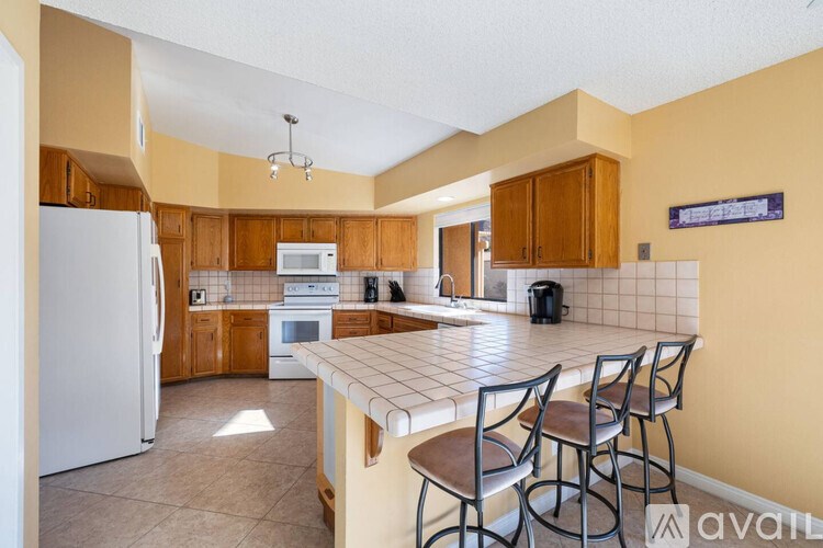 A kitchen with a white refrigerator, wooden cabinets, and a tiled backsplash.
