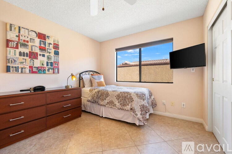 A bedroom with a bed, dresser, and a wall hanging picture.