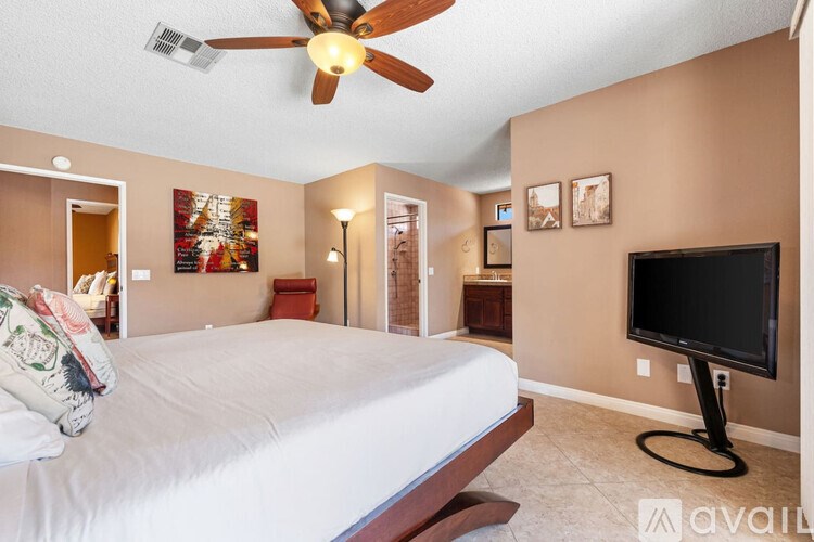 A bedroom with a bed, a ceiling fan, and a television.