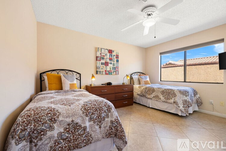 A bedroom with two beds, one with a floral bedspread and the other with a solid bedspread.