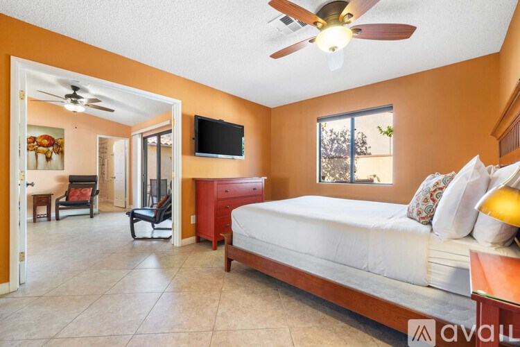 A bedroom with a bed, chair, and television.