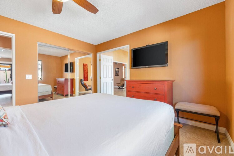 A bedroom with a large bed and a flat screen TV mounted on the wall.