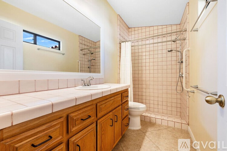 A bathroom with a white sink and brown wooden cabinets.