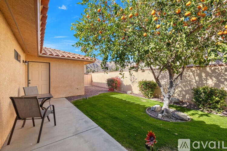 A tree with oranges growing on it is in front of a house.