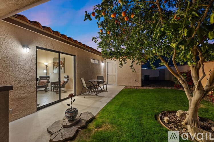A modern house with a patio and a tree with oranges hanging from it.