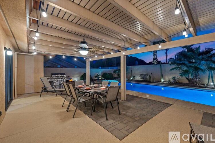 A modern outdoor dining area with a pool and a painting of a palm tree on the wall.
