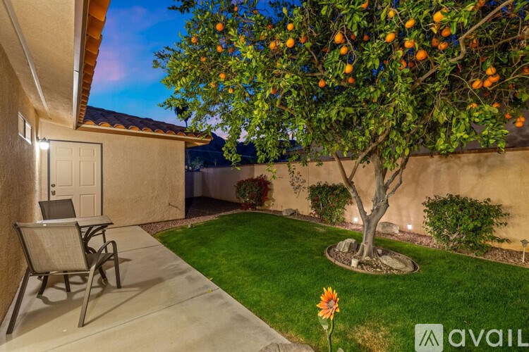 A tree with oranges growing on it is in the foreground of a backyard.