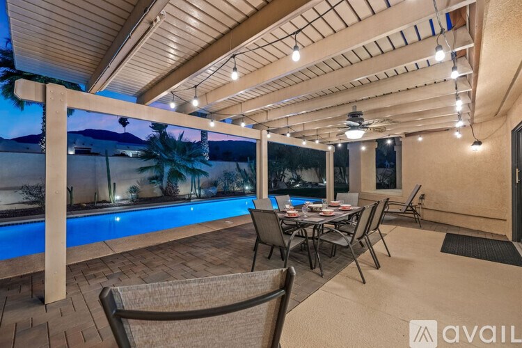 A patio with a table and chairs overlooking a pool.