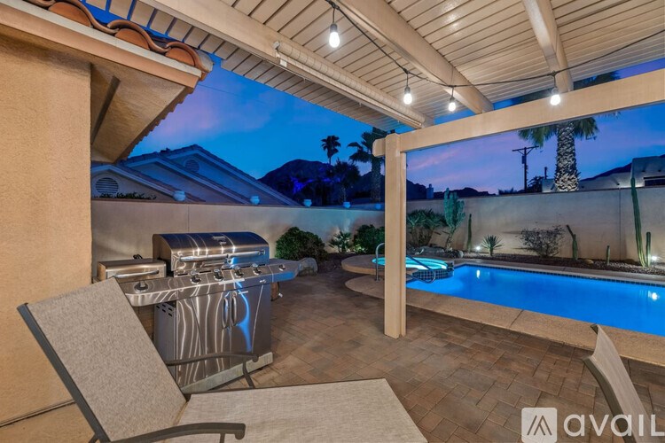 A patio with a table and chairs overlooking a pool.