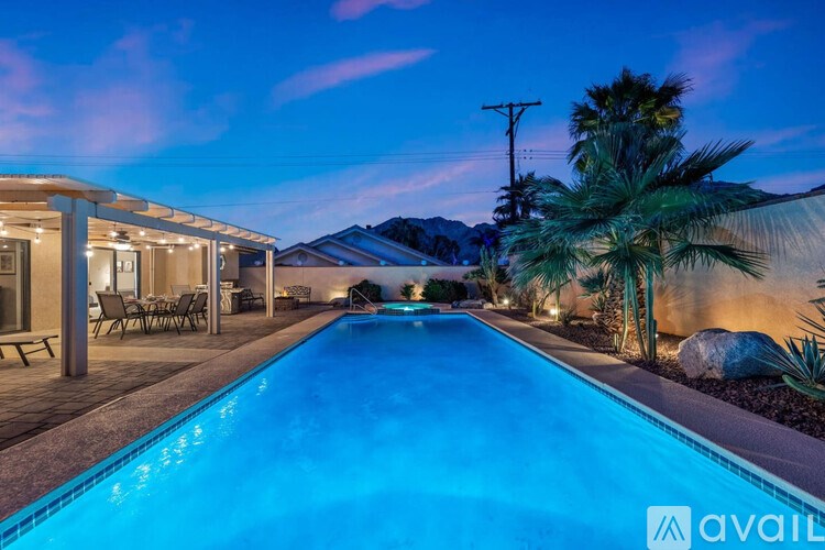 A pool in a backyard with a house and palm trees.