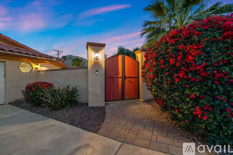 A house with a red door and a wall of red flowers.