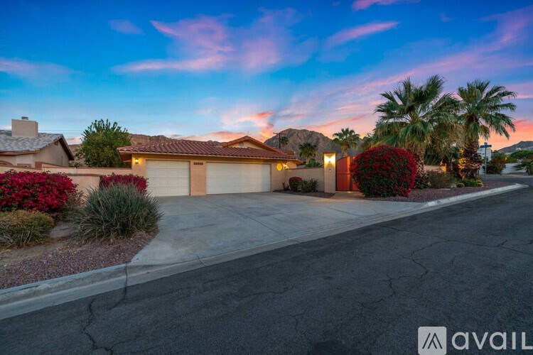 A house with a driveway and palm trees in the background.