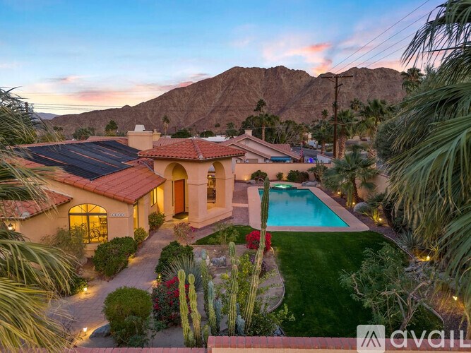 A house with a pool surrounded by greenery and a mountain in the background.
