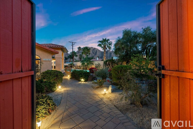 A pathway with lights on either side leading to a house with a mountain in the background.