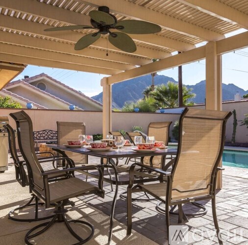 A patio with a table set for a meal and chairs around it.
