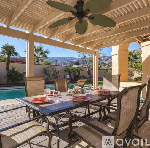 A patio with a table set for a meal and chairs around it.