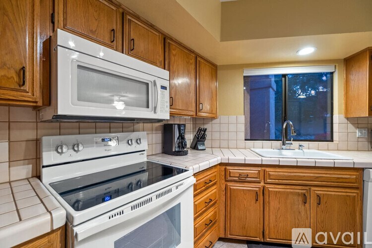 A kitchen with wooden cabinets and a white microwave above the stove.