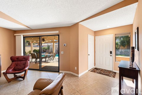 A living room with a red chair and sliding glass doors.