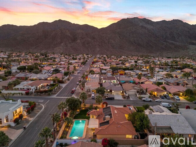 A sunset view of a neighborhood with houses and a pool.