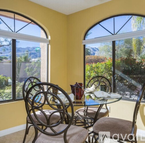 A dining room with a table set for two and a view of the outdoors through the windows.