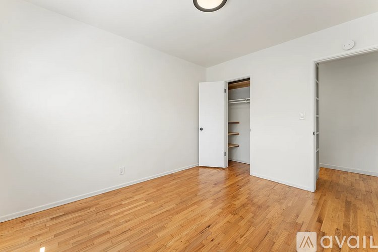A room with a wooden floor and a white wall with a doorway leading to another room.