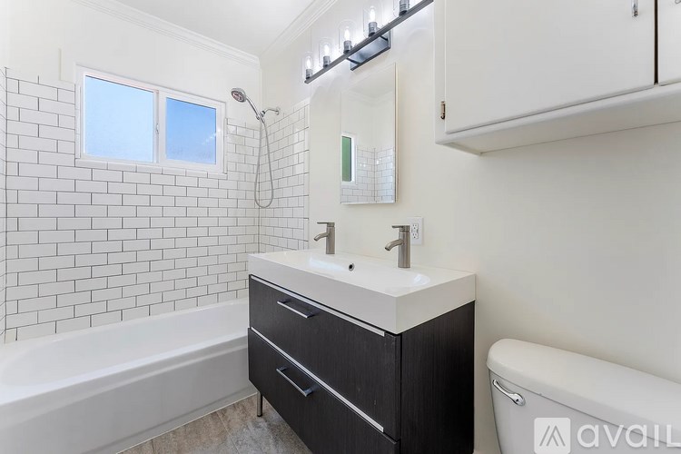 A white bathroom with a black vanity and a bathtub.