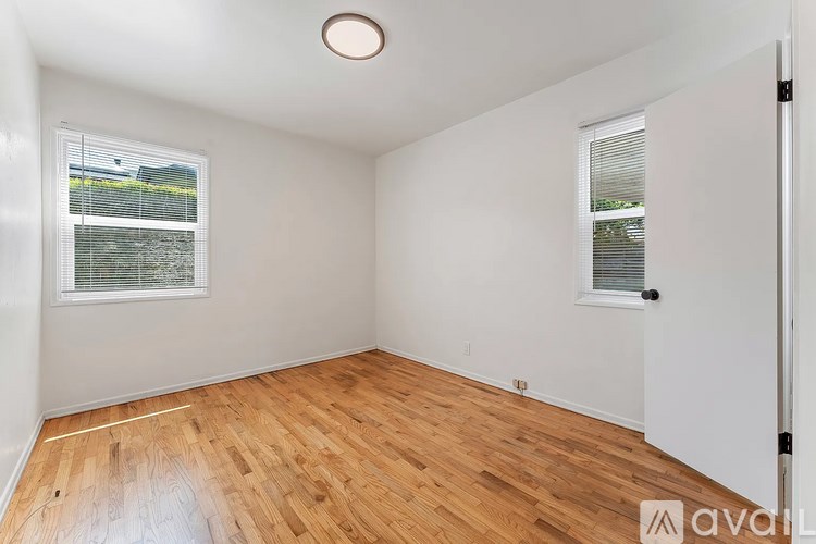 A room with wooden flooring and a window with blinds.