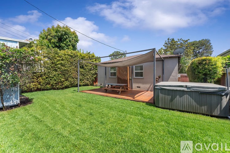 A backyard with a hot tub and a small house.