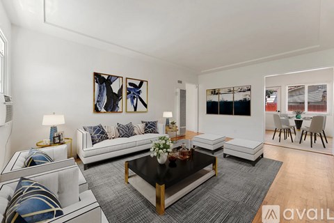 A living room with a white couch, a coffee table, and a painting on the wall.