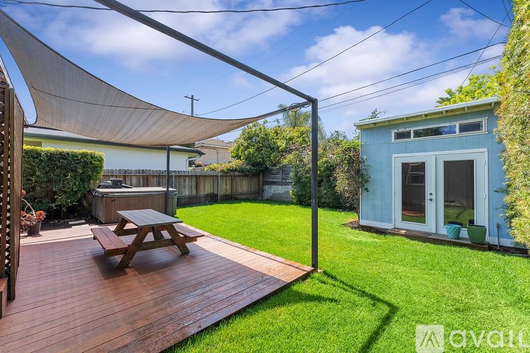A wooden deck with a picnic table and a blue shed in the backyard.